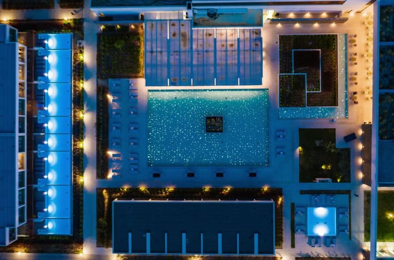Aerial view of a luxury resort pool illuminated at night with fiber optic starry lights.