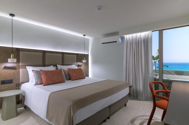 Modern hotel bedroom with a king-size bed, sea view balcony, and elegant interior design.