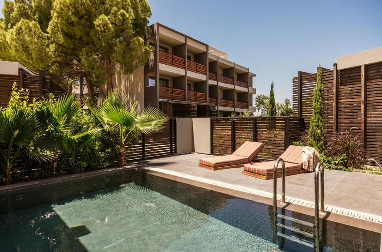Luxury resort pool with two lounge chairs on a private terrace surrounded by tropical palm trees.