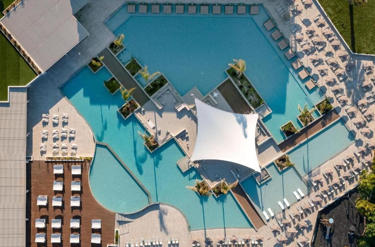 Aerial view of a luxury resort swimming pool with lounge chairs and a modern canopy.