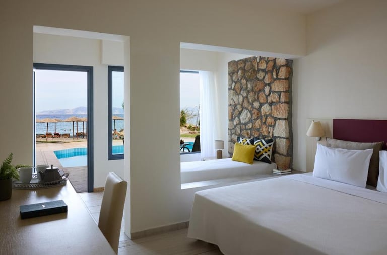 Modern hotel suite with stone wall, sea view balcony, and pool access.