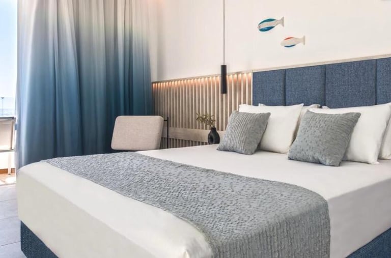 Modern luxury hotel room featuring a blue headboard, ocean views, and nautical decor.