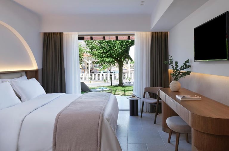 Modern luxury hotel room with a minimalist wooden desk and view of a garden terrace.
