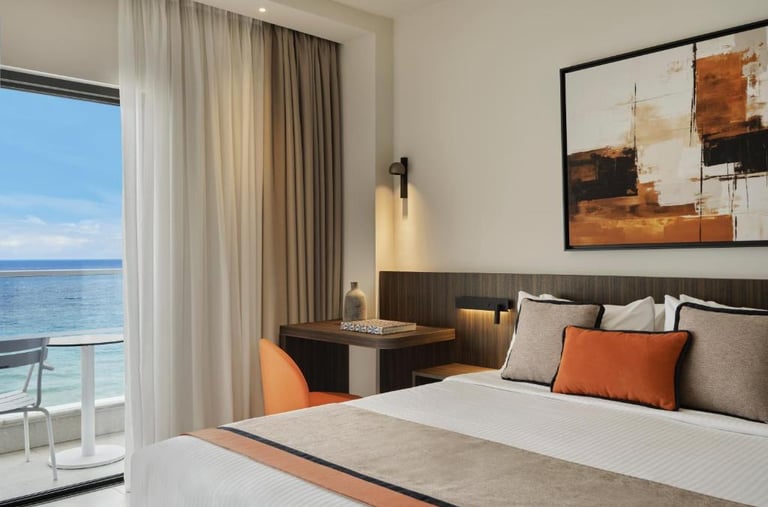 Modern luxury hotel room with king bed, ocean view balcony, and stylish contemporary decor.