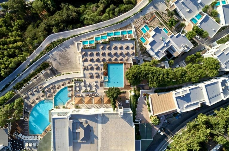Aerial view of a luxury resort with multiple swimming pools, sun loungers, and umbrellas.