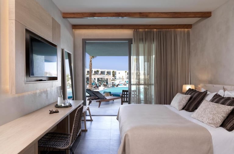 Modern luxury hotel room with wood beams, queen bed, and balcony overlooking a resort swimming pool.