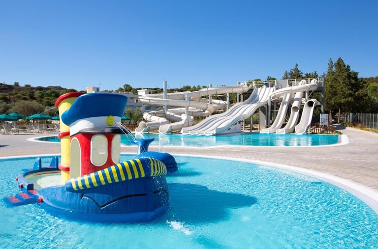 Family water park with colorful boat fountain and multi-lane water slides at a sunny resort.