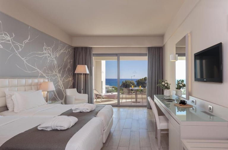 Modern luxury hotel room with twin beds and a private balcony overlooking the blue Mediterranean Sea.