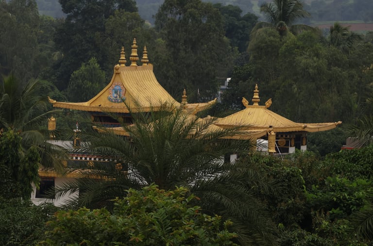 A far view of a Tibetan temple with yellow roofs, surrounded by trees and hills.
