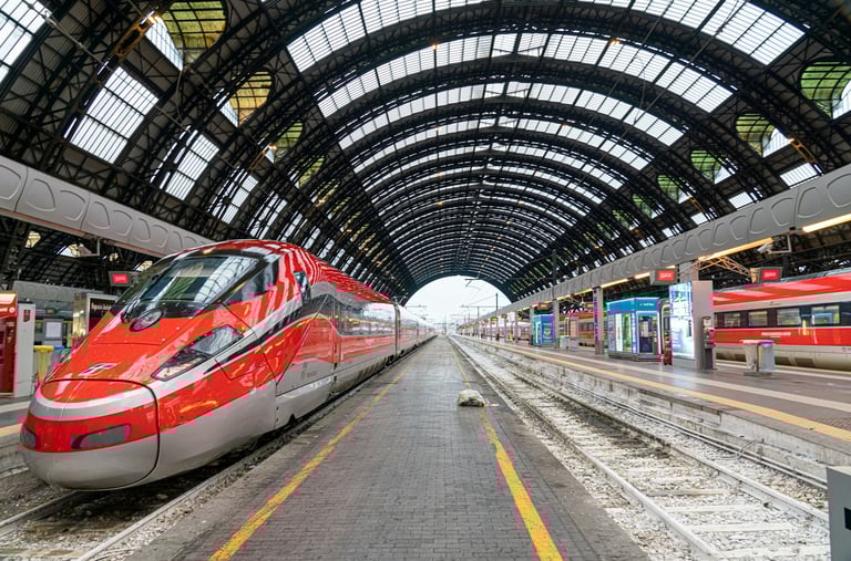 A Trenitalia passenger train standing at a railway station platform