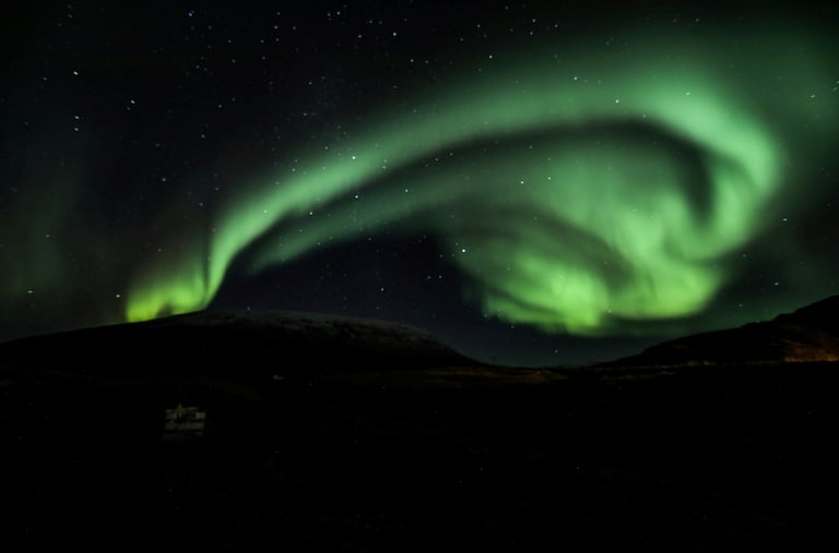 The green ribbon of Northern Lights in the night sky