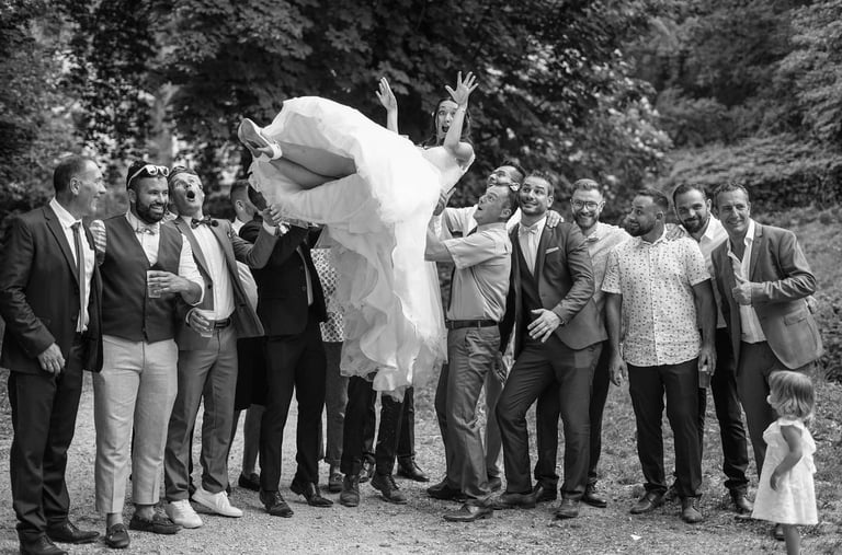 black and white picture of men throwing the bride in the air during a wedding in dijon