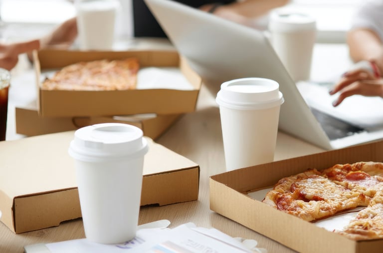 A table with pizza boxes and takeout cups, during a corporate working activity .