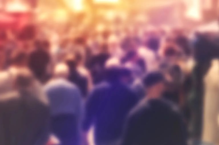 An very diffuse image with a crowd of people walking on a city street.