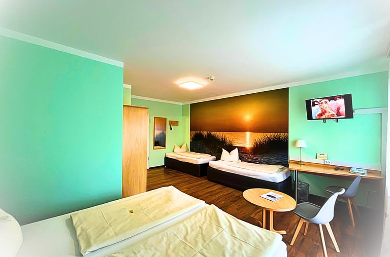 Modern hotel room with green walls, sunset mural, twin beds, and a desk with a TV.