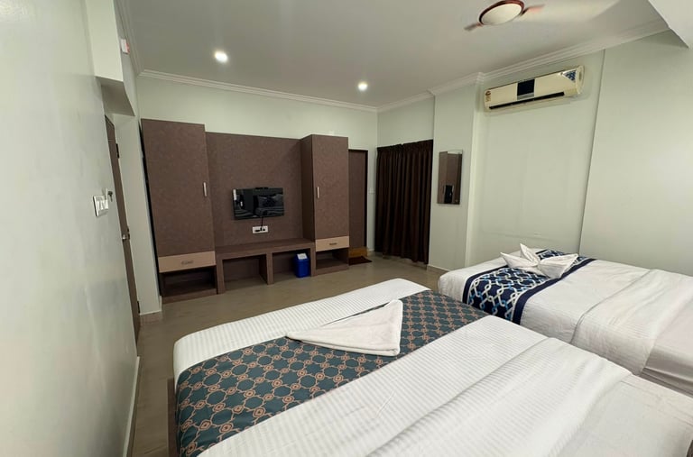 Modern hotel double room featuring twin beds with patterned runners and a wooden wall unit with television.