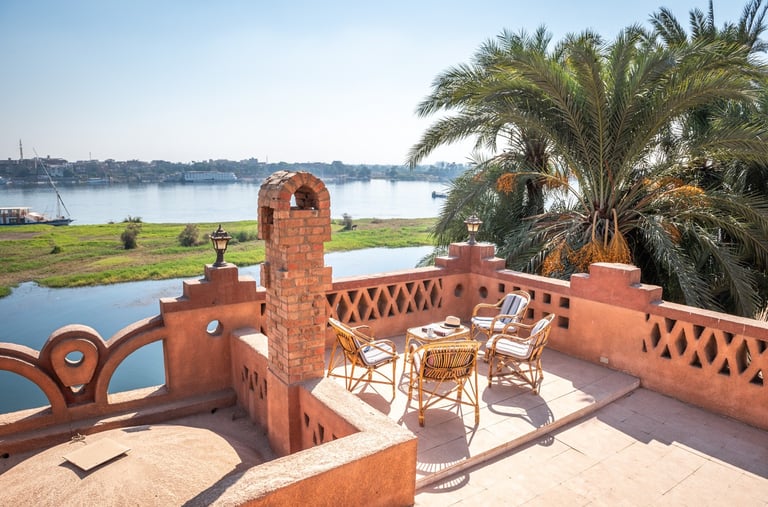 Terrace patio with wicker furniture overlooking the Nile River and palm trees in Egypt.