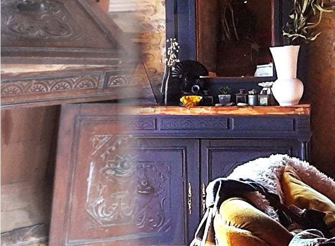 Rustic vintage blue wooden sideboard with ornate carvings in a cozy living room setting.