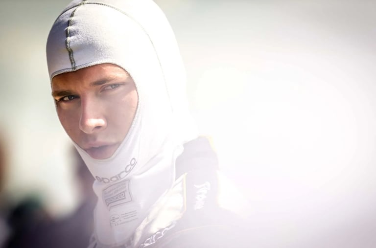 Professional race car driver wearing a white Sparco fireproof balaclava and racing suit.