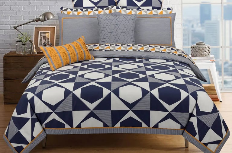 a bed with a blue and white bedding and a white brick wall