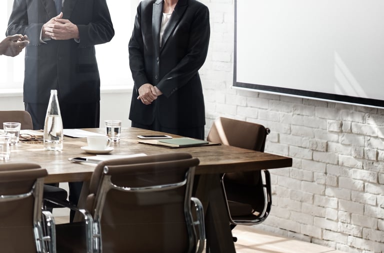  Blurred view of business professionals standing in a meeting room with a table and projector screen