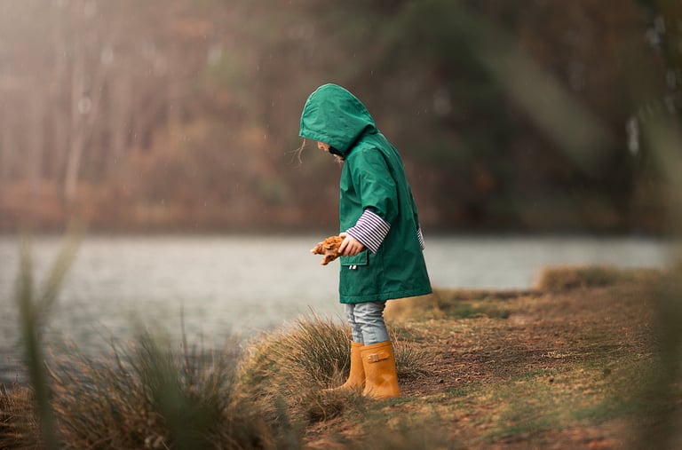 a little girl in a green raincoat and boots