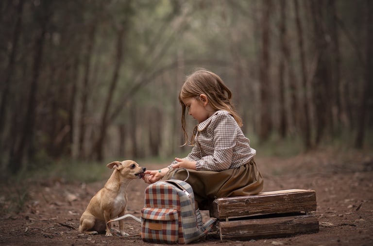 a little girl sitting on a bench with a dog