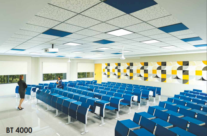 Modern auditorium with blue seating, patterned wall acoustic panels, and drop ceiling tiles.