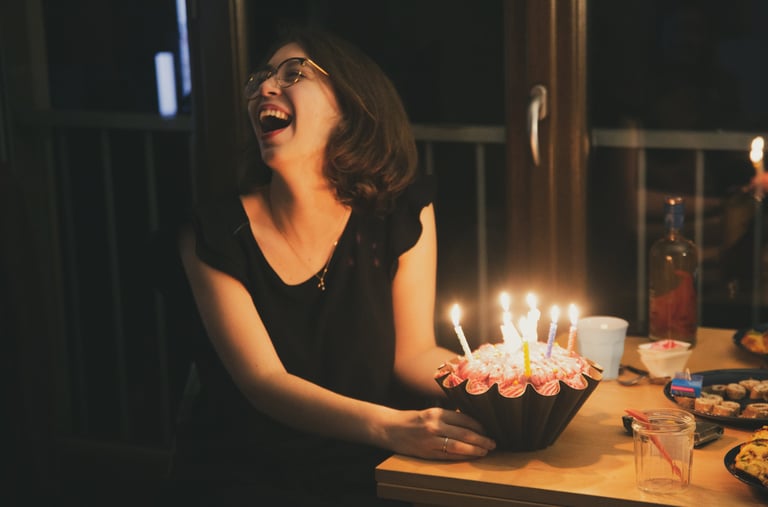 une femme rit aux éclats devant son gateau d'anniversaire, par zohra Elmes