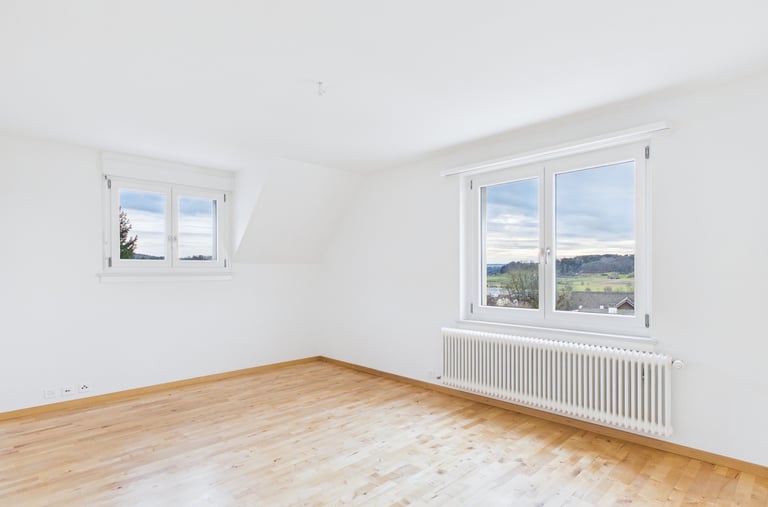 Professionelle Immobilienfotografie: helles Zimmer mit Parkettboden und grossen Fenstern