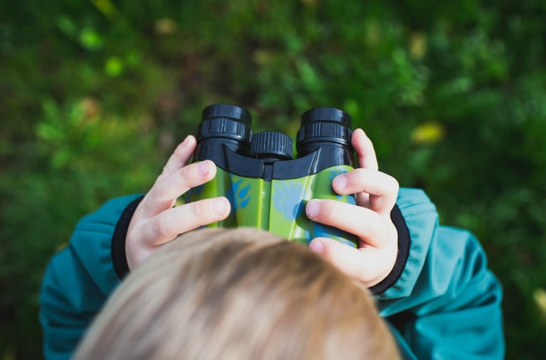 A child looking through binoculars while exploring outside