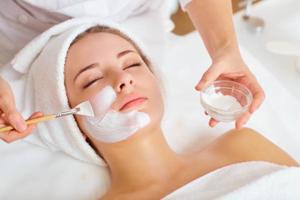 a woman getting a facial mask with a brush