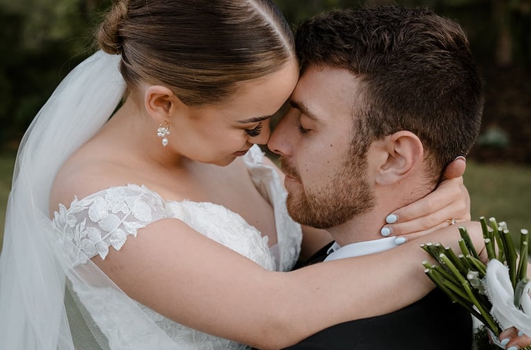 a bride and groom kissing in a field