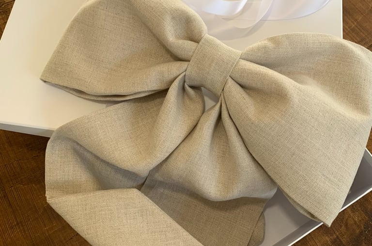 A large bow made from neutral coloured linen on a box