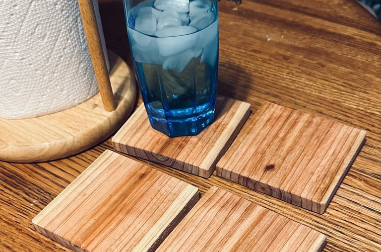a glass of water on a square wooden cedar coaster sitting on a table