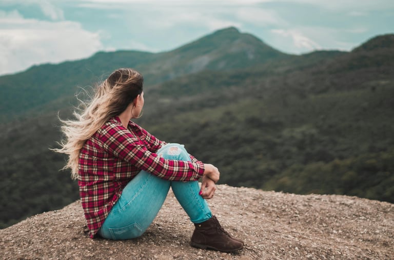 a woman sitting on a rock with her hair in a ponytail