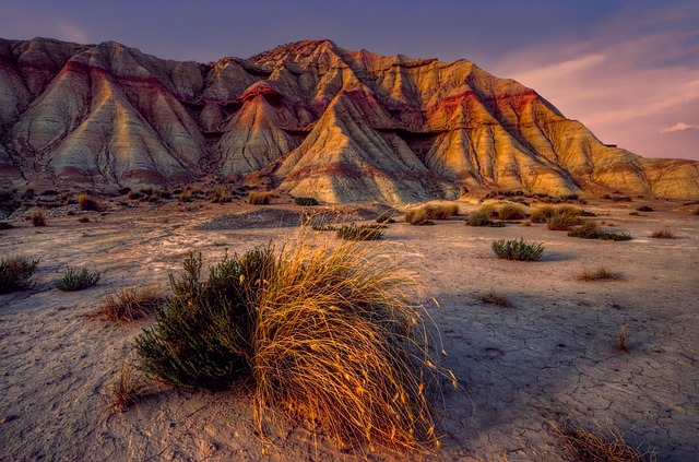 Formación rocosa erosionada con capas de colores rojizos y blancos bajo la luz del atardecer