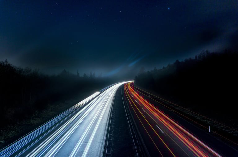 Fast-moving light trails on a highway at night, representing speed, innovation, and technological ad