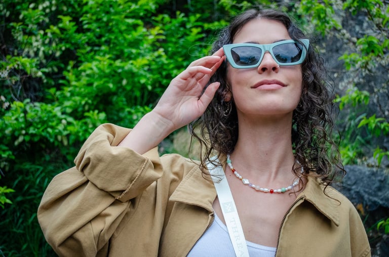 Woman outside looking up and touching her eco-conscious sunglasses