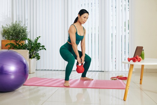 a woman in a green sports bra and a kettle bell