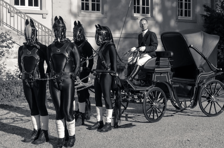 B&W photo of human horses pulling a carriage with driver.