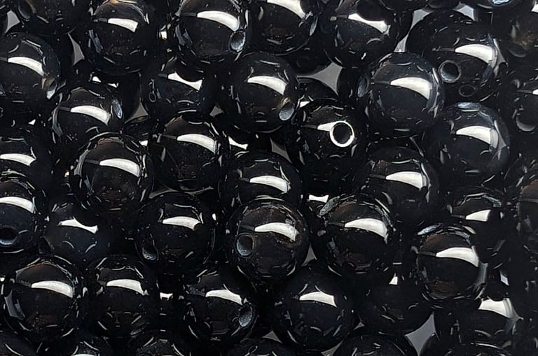 Perles en onyx noir, d’un noir intense avec une finition lisse et brillante, reflétant la lumière