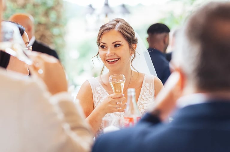 La mariée trinque et sourit pendant le vin d'honneur entourée des invités.