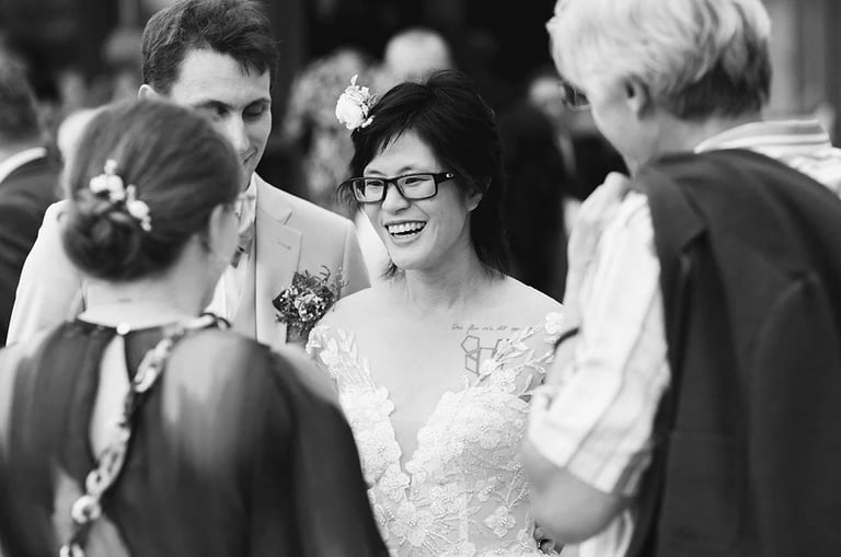 Vin d'honneur en noir et blanc, échanges souriants entre la mariée et ses invités.