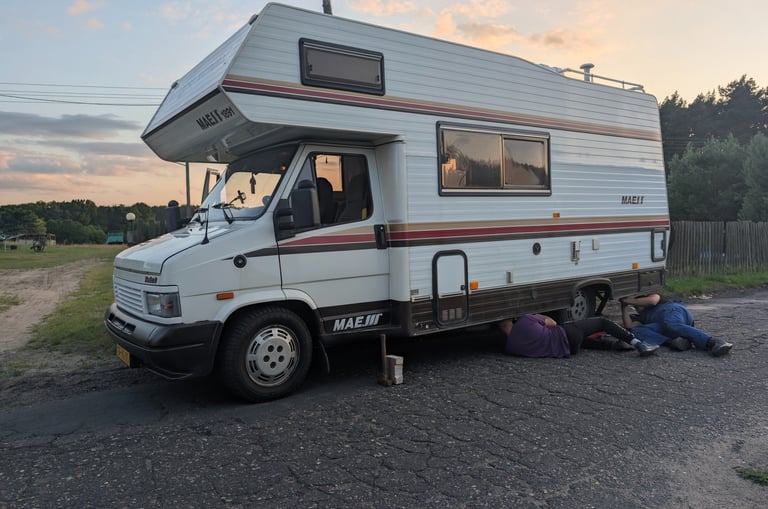 Polish car mechanics working on a broken campervan at the roadside near the German border.