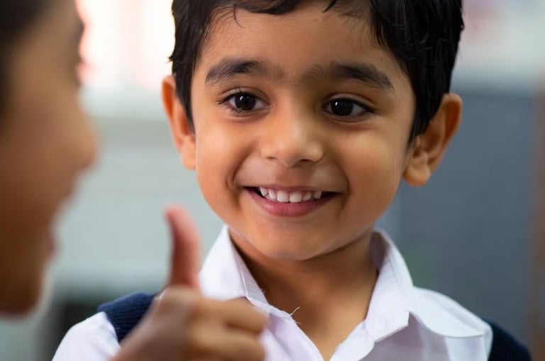 Asian boy with selective mutism gives thumbs up to adult and smiles