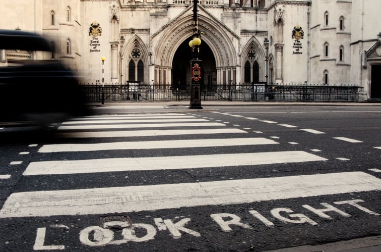 London taxi crossing a zebra pedestrian crossing in front of the Royal Courts of Justice, with “LOOK RIGHT” painted on road