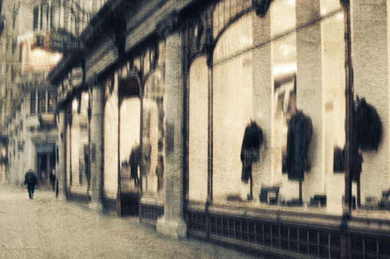 Softly blurred London street scene with a pedestrian walking past illuminated shop windows displaying coats and reflections