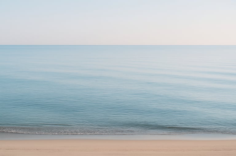 wide shot of a calm sea with empty shoreline, evoking longing and absence.