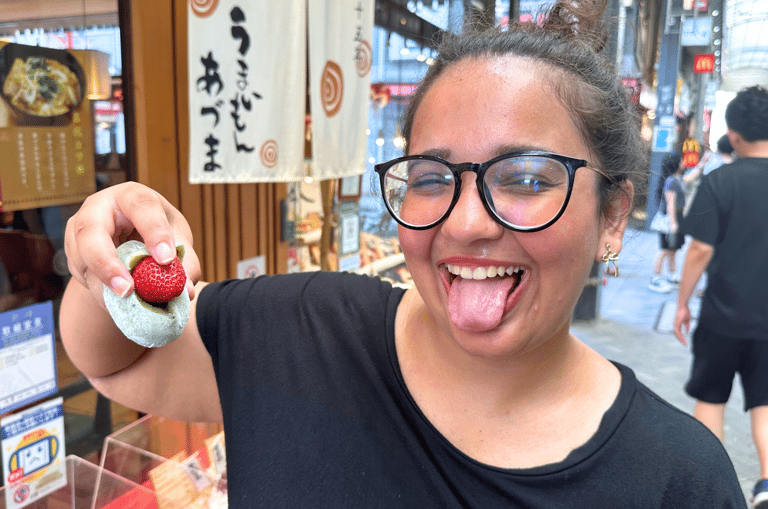 Trisha, a girl making a silly face with her tongue out and holding a Strawberry Mochi